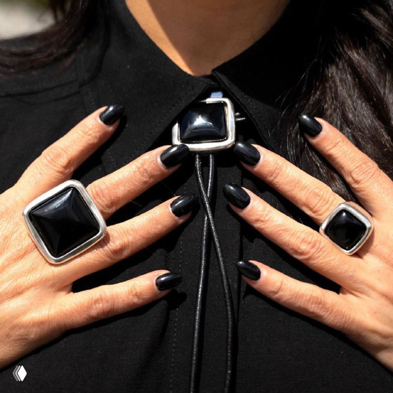 Крупный кадр рук с чёрными квадратными перстнями из коллекции KUBIK, подробно видно форму, полировку и вставки на фоне чёрной одежды