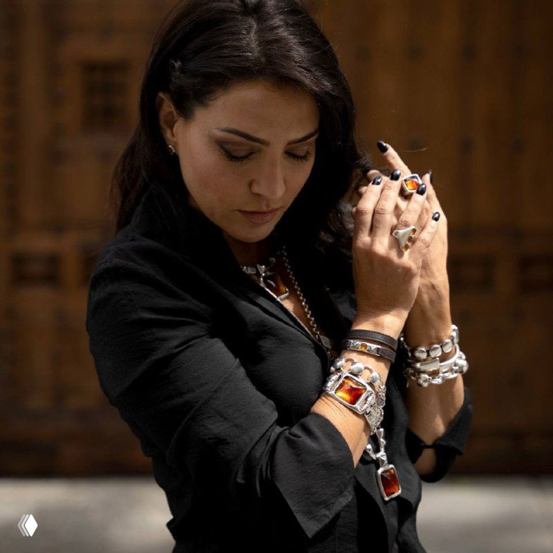 Портретный кадр модели с несколькими браслетами и разноцветными вставками муранского стекла, демонстрация сочетания текстур и украшений на руке
