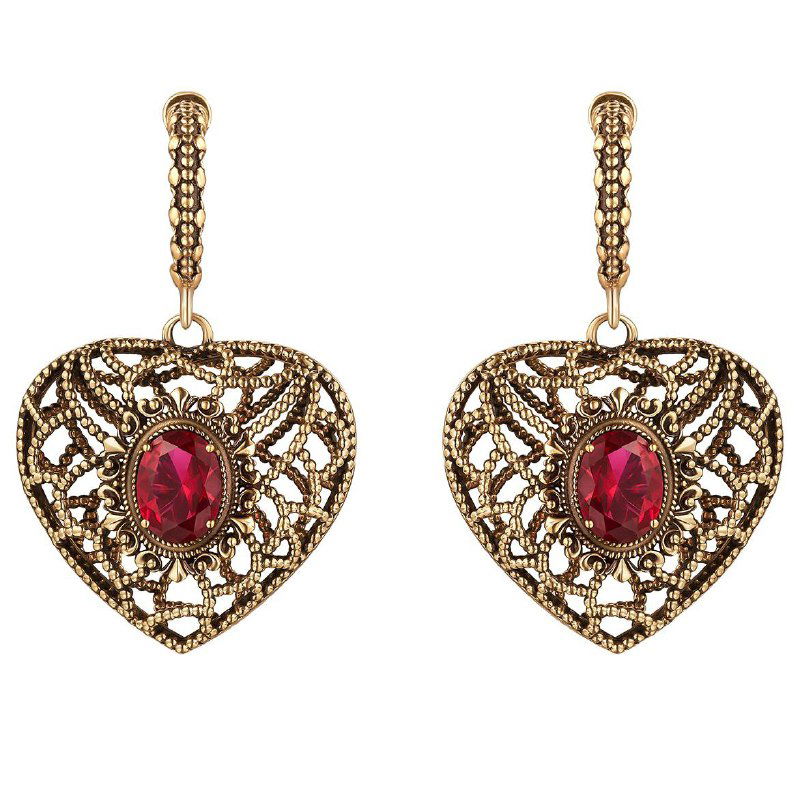 Крупный снимок парных серег в форме сердечка с глубоким красным овальным камнем и витиеватыми ажурными элементами золотистого цвета.