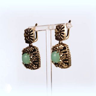 Крупный план пары серёг на подставке: мятный кабошон в ажурной золотообразной оправе, товарное фото на светлом фоне для каталога