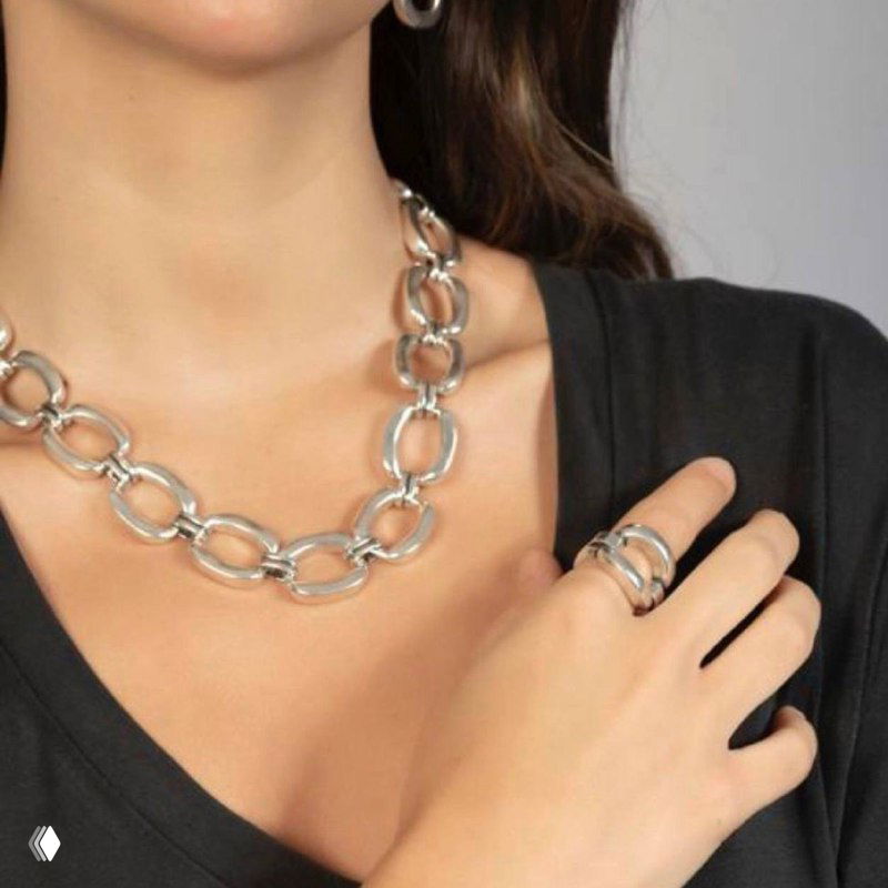 Женщина в тёмной одежде носит цепь с овальными звеньями — фото образа, подчёркивающее посадку украшения и сочетание с кольцом
