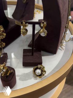 Витрина с золотыми серьгами и кольцом с жемчужиной на бархатных подставках, демонстрация коллекции украшений в магазине Rosone