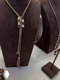 Тонкое золотое колье-галстук на манекене, изящная цепочка с декоративным элементом и инкрустацией мелких камней в стиле Claudio Canzian