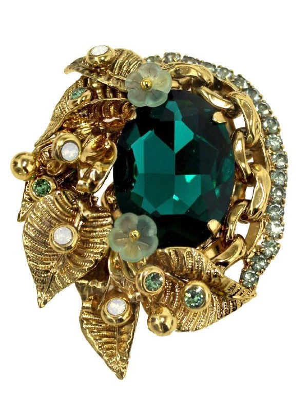 Крупный план броши с большим зелёным кристаллом, золотыми листочками и множеством мелких декоративных камней и страз, художественная отделка