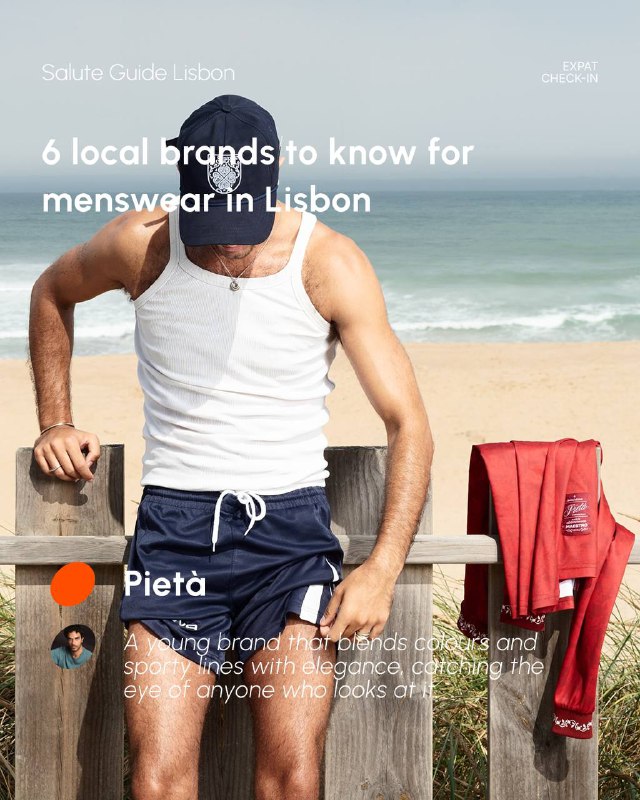 Beached portrait of a shirtless male model wearing swim shorts with a jacket draped nearby, evoking summer menswear and coastal lifestyle imagery.