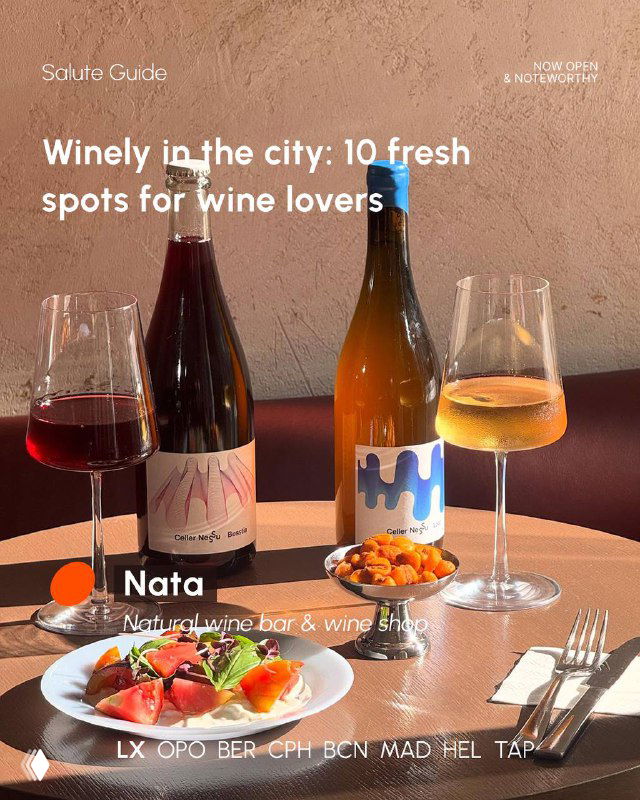 Two wine glasses and two bottles on a table beside small plates, intimate setting that highlights natural wines and small-plates dining in a city bar.