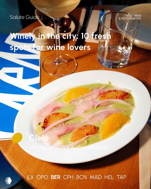 Close-up of a plated dish with citrus and pickled vegetables on a table beside a wine glass, representing simple dining paired with natural wine.