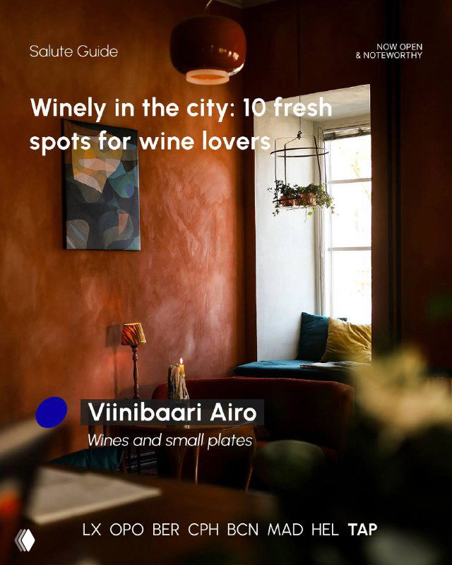 Cozy booth by a window with soft cushions and a small table, moody colours and natural light framing a relaxed wine bar interior.