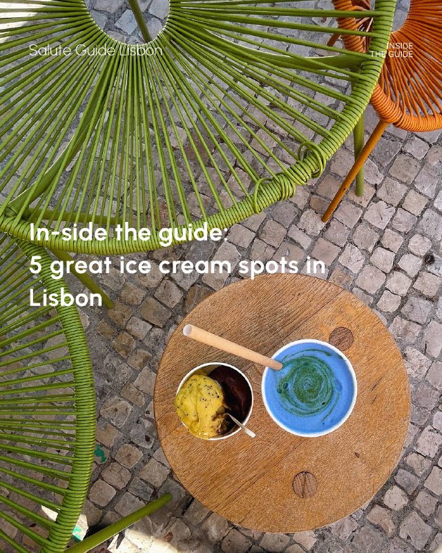 Top-down photo of a small outdoor café table on Lisbon cobblestones showing two cups of ice cream and colourful woven chairs.
