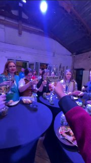 За круглым столом участники поднимают бокалы и общаются в тёплом освещении: неформальная беседа и еда создают чувство команды и близости.