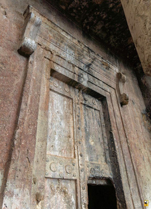 Деталь каменного портала гробницы: массивная дверь, орнаментальные элементы и естественные трещины, крупный план исторического входа в пещерное захоронение.