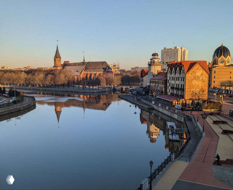 Панорамный вид на набережную и остров Канта в Калининграде при спокойной воде, видно Кафедральный собор и отражение архитектуры в реке вечером.
