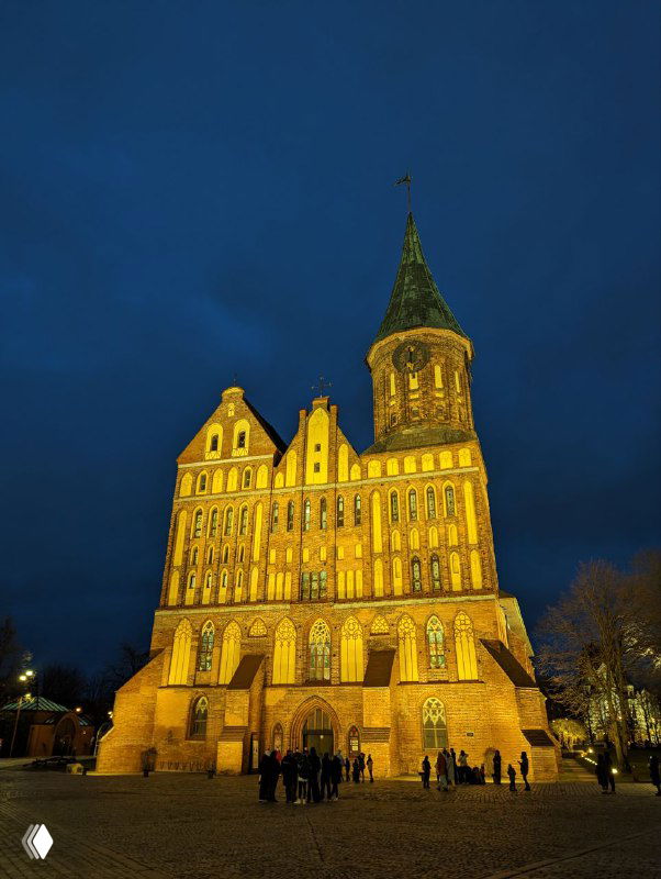 Ночное освещение фасада Кафедрального собора в Калининграде: крупный план подсвеченного кирпичного готического фасада и входной части здания.