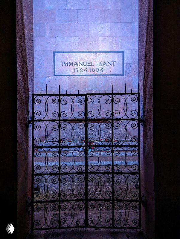 Каменная плита с надписью IMMANUEL KANT внутри мемориального пространства собора, ограждение и приглушенное освещение вокруг могилы философа.