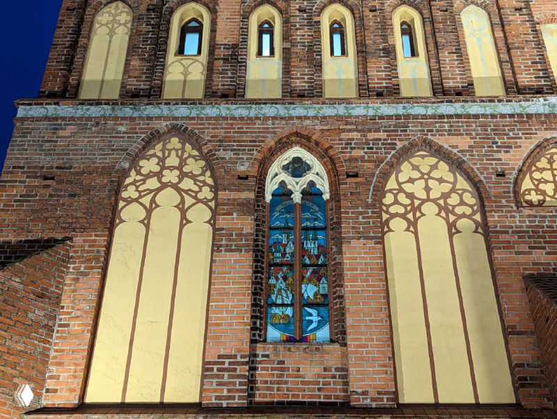 Деталь архитектуры Кафедрального собора: витражи и декоративные арки на кирпичном фасаде, вид дневного освещения на отделке стен.