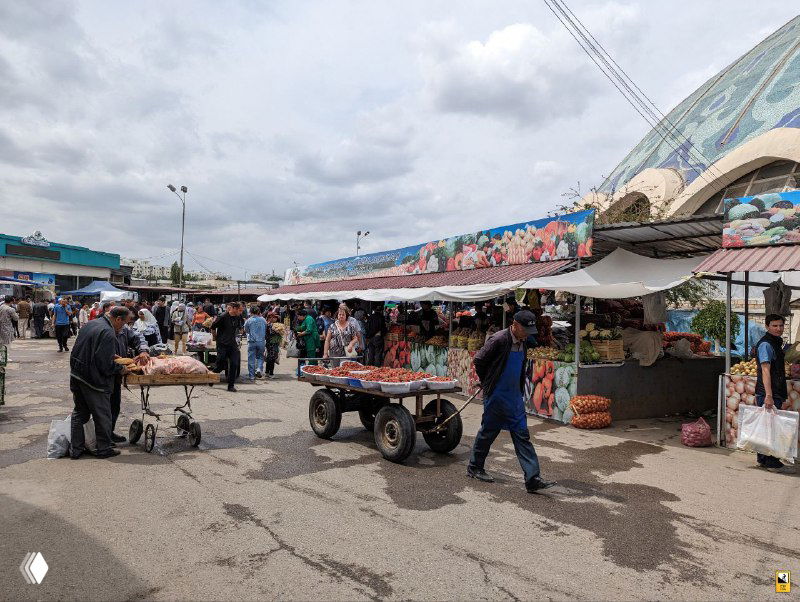 Общий вид торговой площади у входа на Чорсу: люди, тележки и киоски под открытым небом создают многолюдную базарную сцену и динамику повседневной торговли.