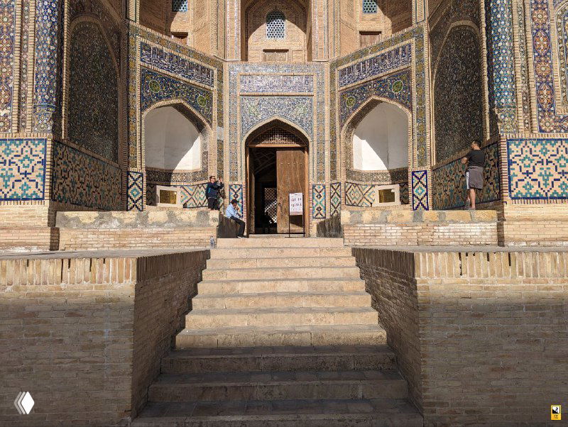 Каменная лестница и портал медресе с декором из кафеля в Бухаре; ступени ведут к массивному входу с орнаментом и резьбой.