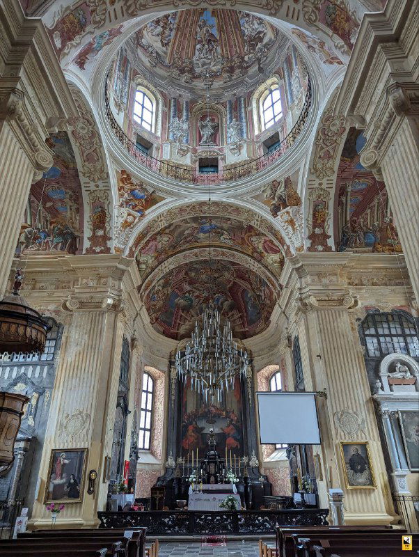 Интерьер костела: высокий неф с богато расписанными куполами и фресками, алтарная часть и орган, передающий величественную атмосферу барокко.