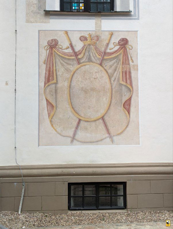 Остатки настенной росписи на внешней стене костела: декоративный щит и следы исторических живописных слоёв, обнаруженные реставраторами.