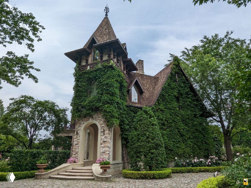 Башенчатый дом в нормандском стиле, обвитый плющом, на фоне зелёных насаждений — атмосферная архитектура усадьбы Ореховно.
