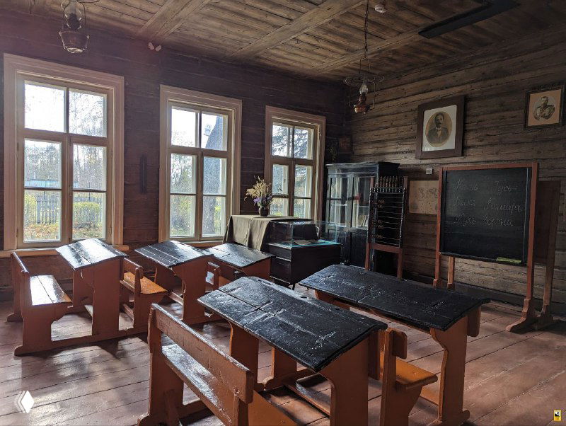 Интерьер дореволюционной земской школы в Мелихове: деревянные парты и скамьи, широкие окна и старинная классная доска в музейной экспозиции.