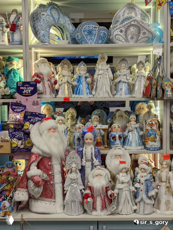 Витрина с коллекцией кукол и фигурок Снегурочки и Деда Мороза в сувенирном магазине — множество ручных изделий и фабричных сувениров.