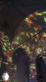 Лазерные проекции на сводах Кафедрального собора во время новогоднего концерта: цветные узоры света, заполнённый зал и праздничная атмосфера внутри собора.