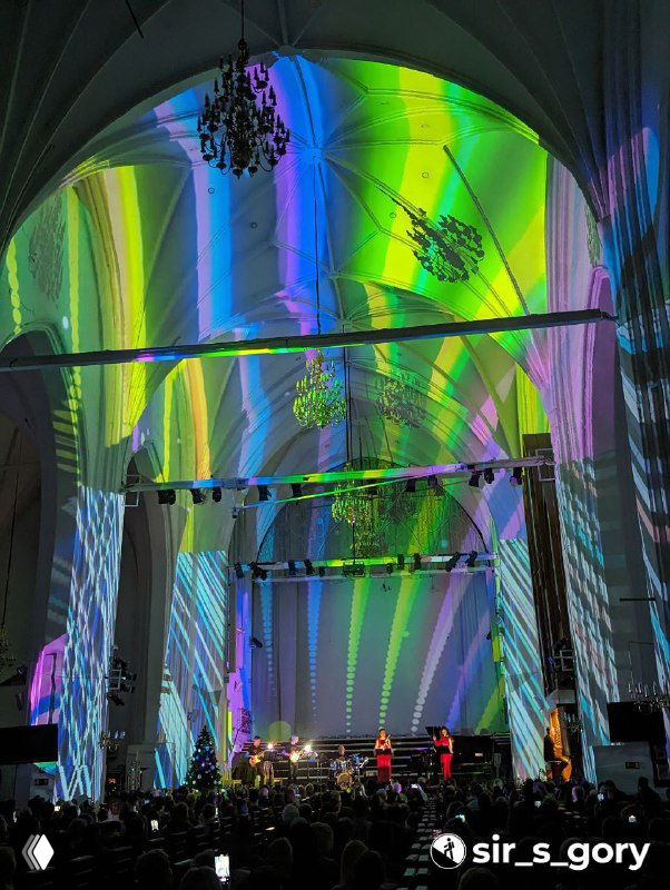 Широкий план сводов собора с зелёно-жёлтыми световыми эффектами; архитектурные арки подсвечены, создавая драматическую праздничную картину.