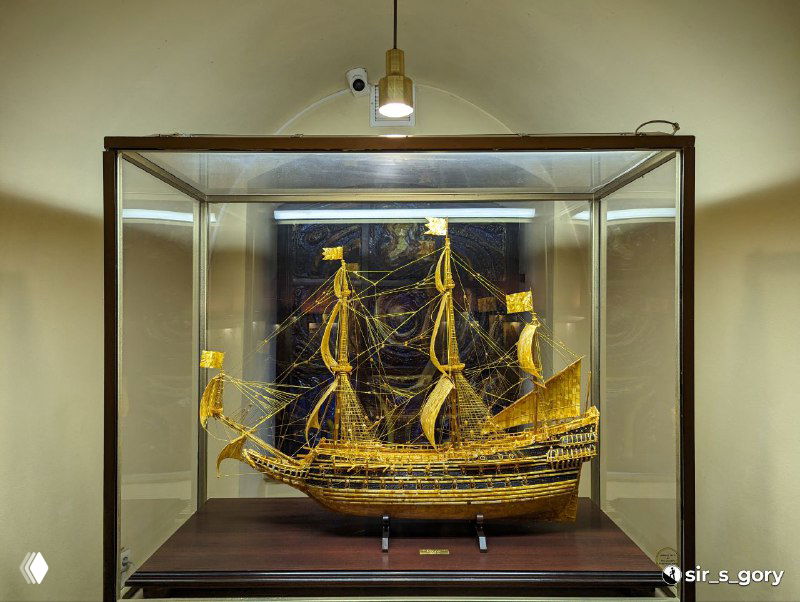 Детальная модель парусного корабля, выполненная из янтаря и представлена в стеклянном кубе с музейной подсветкой.