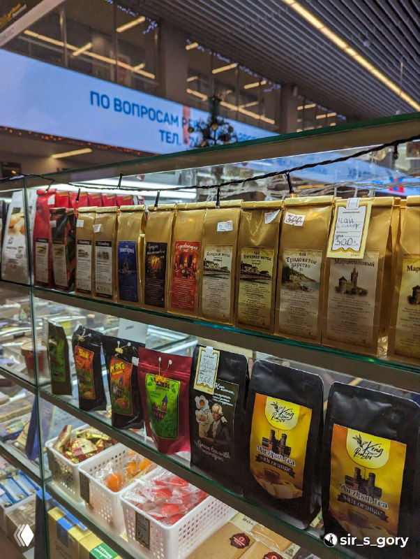 Полки в магазине с разными упаковками сувениров и продуктовых подарков: кофе, специи и сладости в пакетах — вид в торговом отделе сувениров.