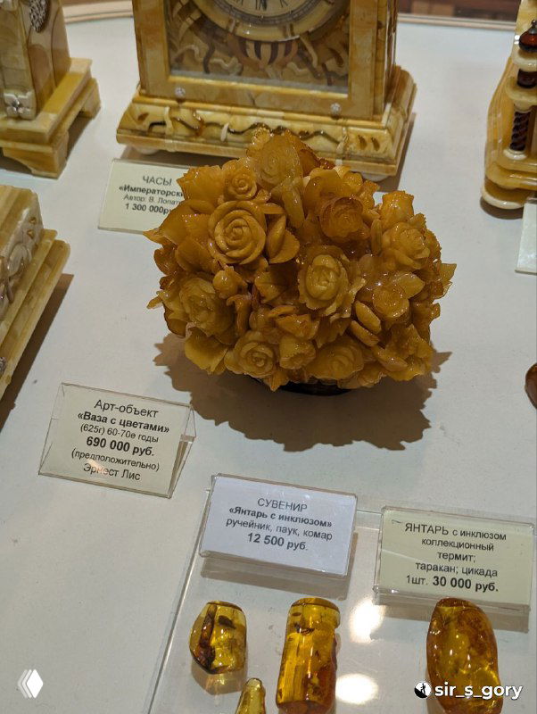 Витрина с изделиями из янтаря: сувениры, статуэтки и ценники, крупный кусок янтаря и ценовые бирки — музейно-магазинный экспонат.