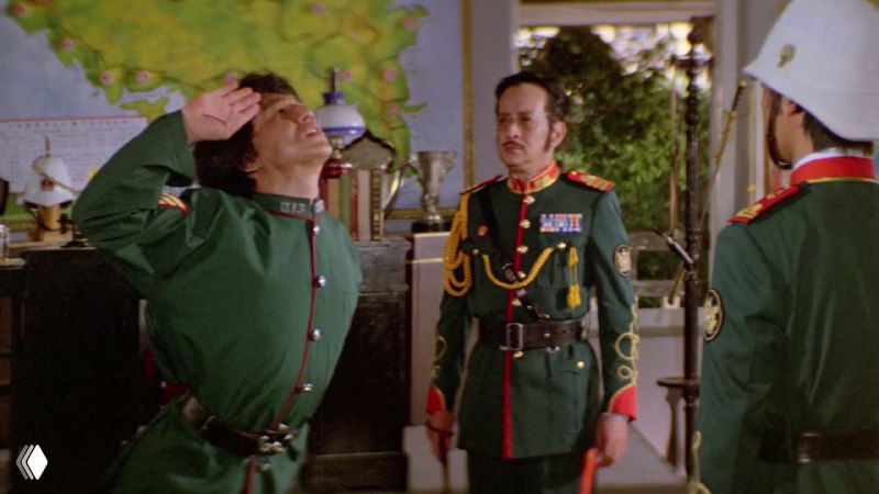 Кадр из фильма «Проект А» с Джеки Чаном в военной форме — комический эпизод в интерьере, демонстрирующий театральную постановку боя и гротескные действия.