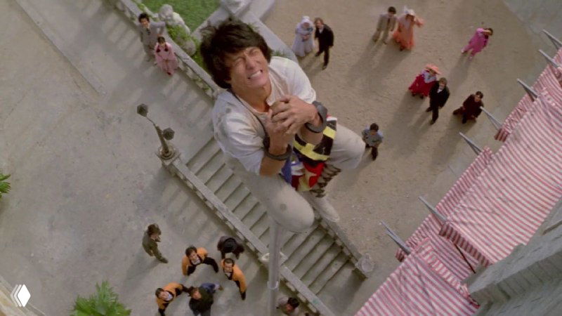 Джеки Чан в динамическом плане сверху — трюк с падением и акцентом на кинетическую композицию, подчёркивающий мастерство каскадёров фильма.