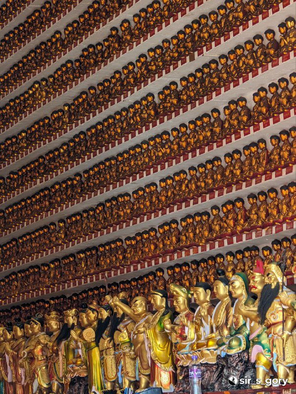 Стена из множества маленьких фигурок Будд, выстроенных рядами внутри комплекса Монастыря десяти тысяч Будд, эффект монохромного золота.