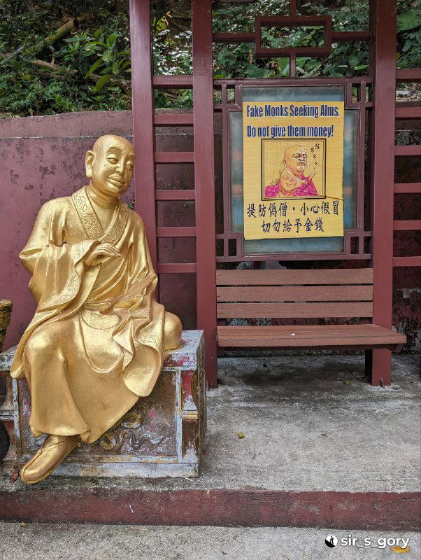 Одна позолоченная фигура Будды у стены и рядом предупреждающая табличка, показывающая бытовую сторону комплекса и советы посетителям.