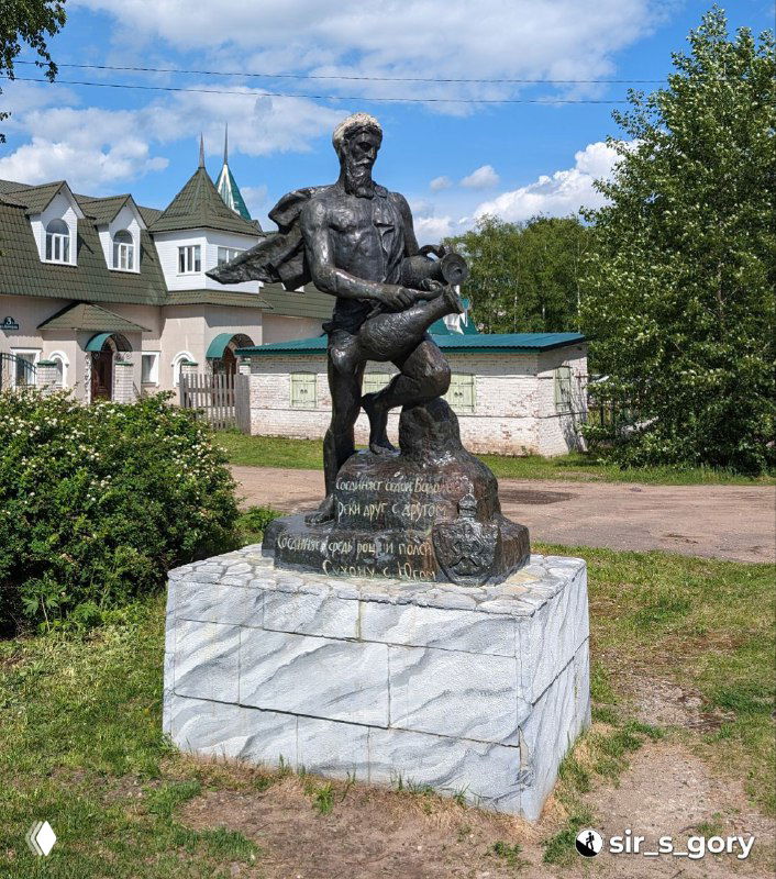 Скульптурная композиция фигуры уличного героя на постаменте на фоне горожанских зданий и летнего неба, городской элемент в исторической среде.