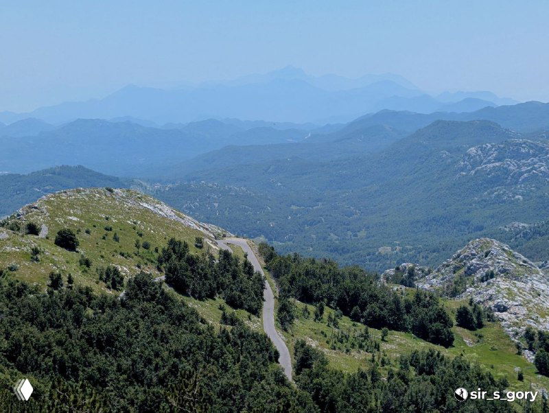 Панорамный вид с Ловчена на горные хребты и долины под ясным небом, расстояние и растительность видны на переднем и среднем плане.