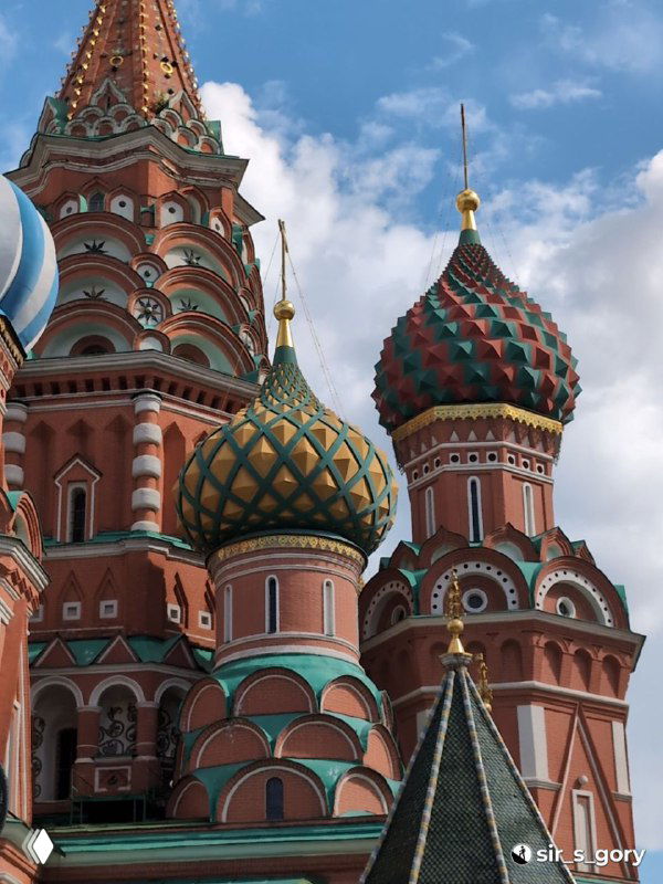 Крупный план двух луковичных куполов собора: геометрический орнамент, контраст зелёно‑жёлтых и красных оттенков на фоне неба.