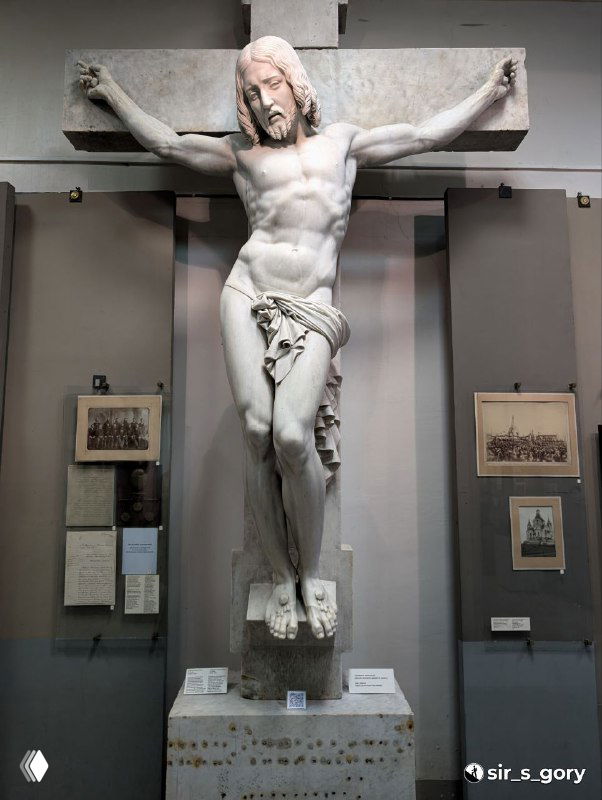 Мраморная скульптура распятого Иисуса в выставочном зале Нижнетагильского музея‑заповедника «Горнозаводской Урал», вид в полный рост и музейный контекст.