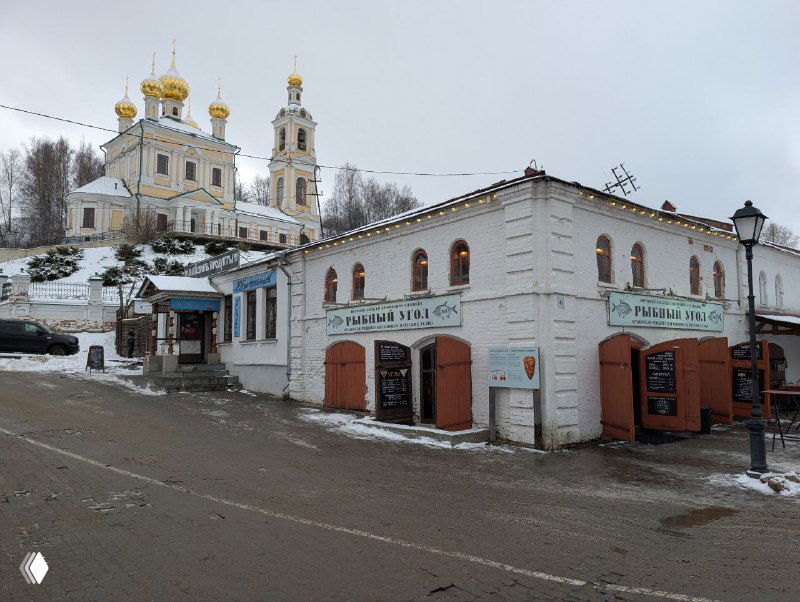 Улица Зимнего Плёса зимой: домики и церковь на холме, заснеженная дорога и архитектурный ансамбль у реки в небольшом городке.