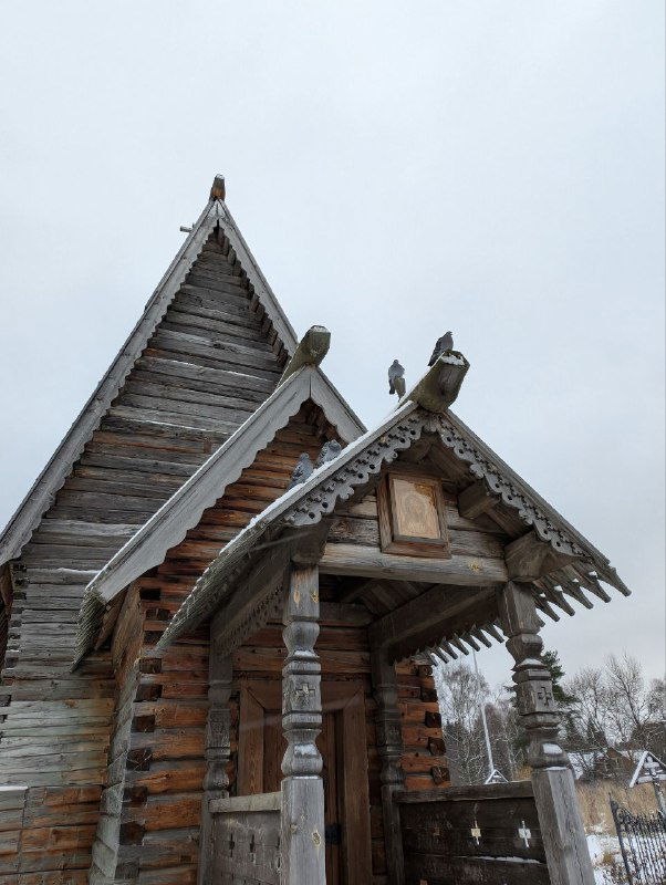 Деревянная крыша с резными украшениями и наличниками на фоне серого зимнего неба — пример народного зодчества Плёса.