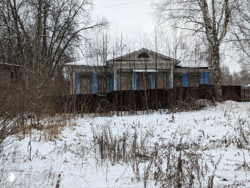 Заброшенный или ветхий деревянный дом среди редких деревьев и сугробов — вид зимней окраины Плёса с традиционной застройкой.