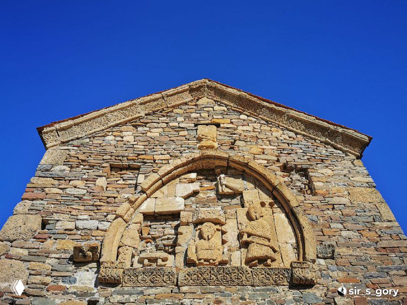 Арочный элемент и барельеф на фасаде храма Тхаба-Ерды в крупном плане, видны композиция из фигур и каменная фактура под ярким небом.