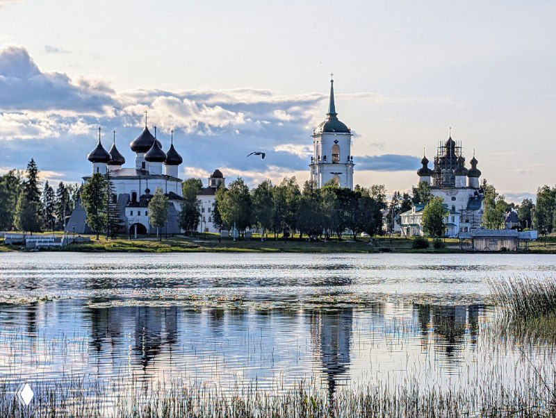 Вид на Соборную площадь и Собор Рождества Христова с другой стороны реки Онега: отражение в воде, вечернее небо и спокойная водная гладь.