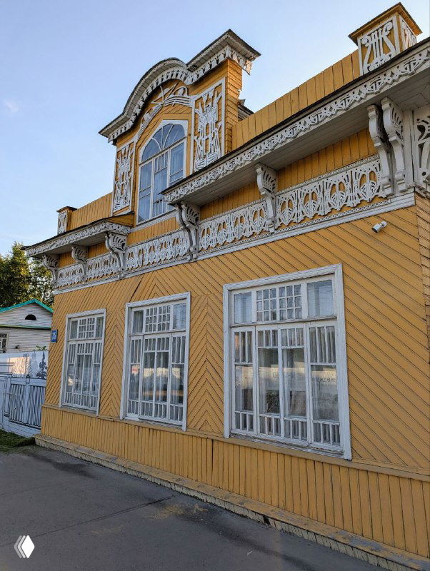 Деревянный особняк в Вологде с характерным декором в виде ажурной резьбы и декоративным фронтоном над высоким окном на втором этаже