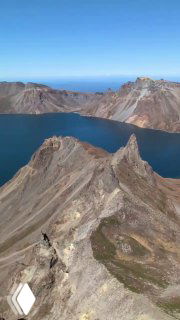Панорамный вид на острую гряду внутри кратера и гладь озера Чон, с куполообразными склонами и бирюзовой водой.