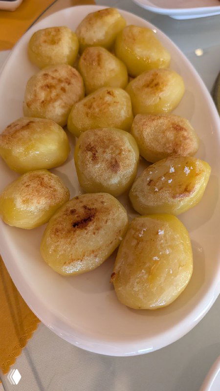 Тарелка с маленькими печёными картофелинами в золотистой корочке, масляная глазурь, крупный план, домашняя сервировка.