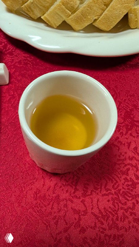 Чашка с тёмно-жёлтым картофельным чаем на столе рядом с хлебом и скатертью — необычный напиток из поездки автора.