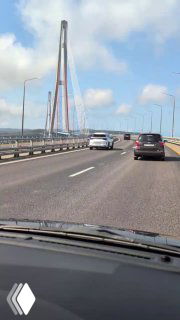 Движение по Золотому мосту снято из салона машины: авто на проезжей части, дорожное полотно и вид на сталежелезные пилоны моста.