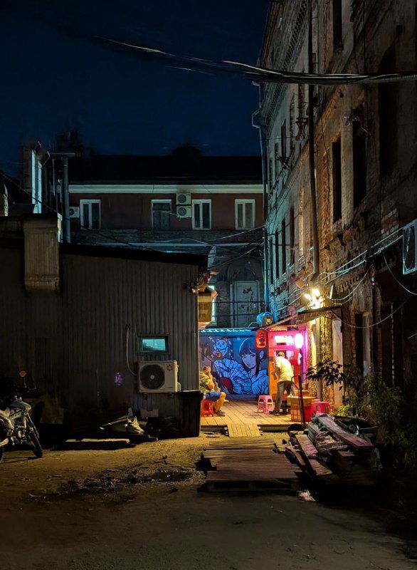 Тёмный проход и двор с неоновой подсветкой и граффити у входа — уличная сцена ночной Миллионки с небольшими заведениями и вывесками.
